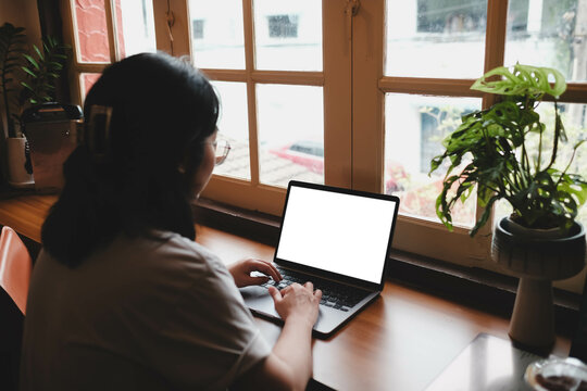 Woman working at cafe table with laptop displaying blank white screen, coffee in red cup and smartphone placed on terrazzo surface.