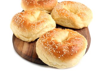 Wooden board of tasty bagels with sesame seeds on white background, closeup