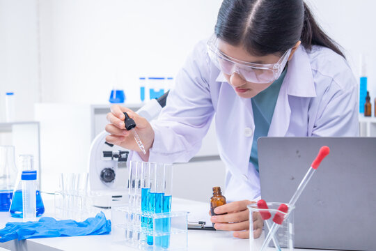 Teen scientist girl conducting science test by carefully evaluating blue solution in laboratory. Science, laboratory, experiment, and research demonstrate academic progress and practical skills.