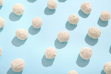 Many white chocolate candies with coconut topping on blue background