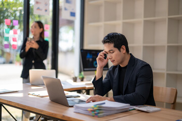 A man is talking on his cell phone while sitting at a desk