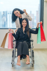 multiracial female friends with shopping bags in the urban building,a woman and a disability person on wheelchair enjoy shopping in the mall