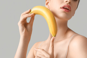 Young woman with banana on light background, closeup. Sex concept