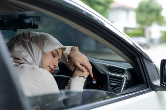 Muslim women sleep inside car on steering wheel. Feeling drowsy while driving. When you feel sleepy, you should stop driving to rest.