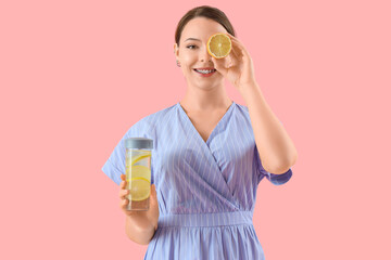 Young woman with lemon and bottle of water on pink background