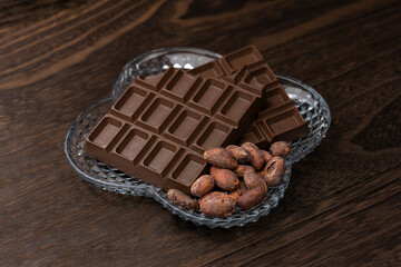 ガラス皿に盛りつけた板チョコレートとローストカカオ豆