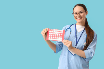 Female doctor with menstrual calendar on blue background