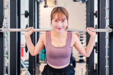 ジムで筋トレをするスポーティーな若い女性
