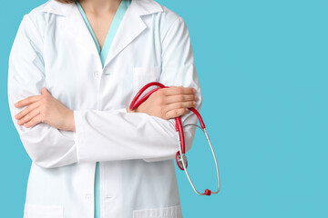 Female cardiologist with stethoscope on blue background, closeup
