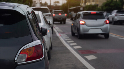 Traffic jam with several vehicles lined up on a road. Close up car with its tail lights of parking car. Traffic conditions are clear in the morning.