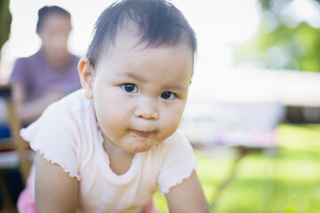 Curious baby enjoys leisure time outdoors with family during picnic while people relax in background creating warm and joyful concept of togetherness and care