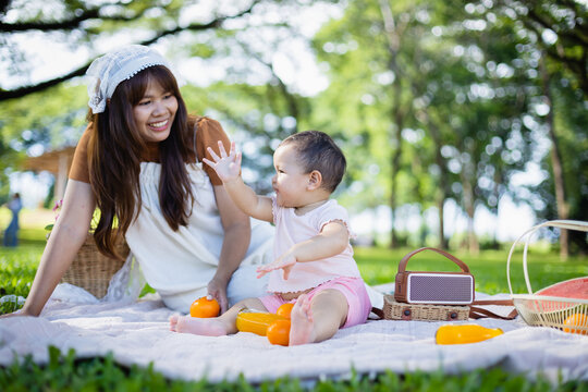 Family enjoys leisure picnic in park with people relaxing on blanket surrounded by trees and fresh air, capturing joyful concept of spending time together outdoors