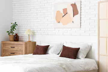 Interior of light room with big bed, commode and painting