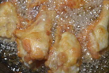 Chicken legs deep-fried to perfection in hot oil, freshly cooked.