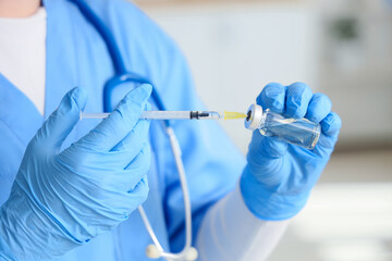 Female doctor with vaccine and syringe in clinic, closeup