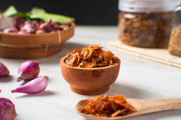 Bawang Goreng or Fried red onions in a wooden bowl. Crispy onion fries or shallots are fried to a golden brown color. Crispy fried onions. 