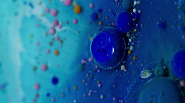 Vertical video. Bubble spill. Ink flow. Oil colorful drops exploding dissolving in blue fluid. Acrylic pigments floating in water abstract art background.