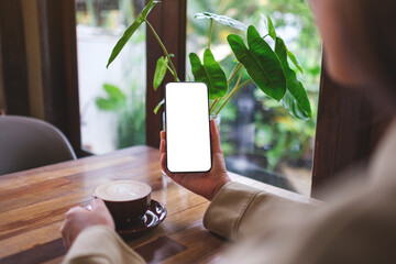 Mockup image of a woman holding mobile phone with blank screen while drinking coffee