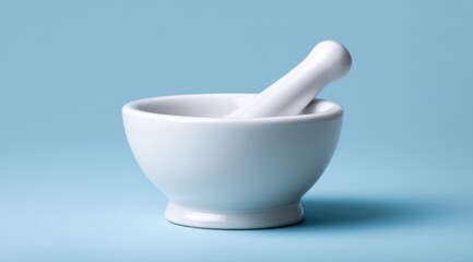 A pristine white ceramic mortar and pestle rest on a pale blue background, casting a subtle shadow