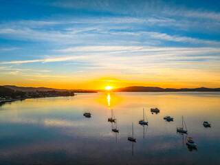 Sunrise with high cloud, boats and reflections over the water