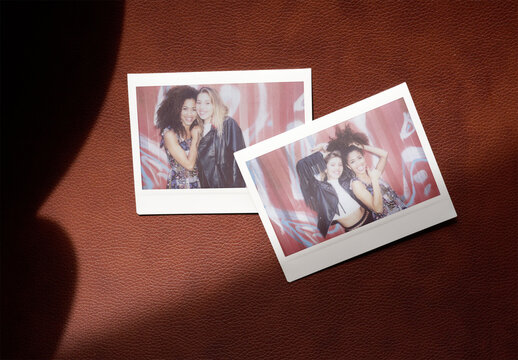 Template of Two blank polaroids lay on a leather surface.