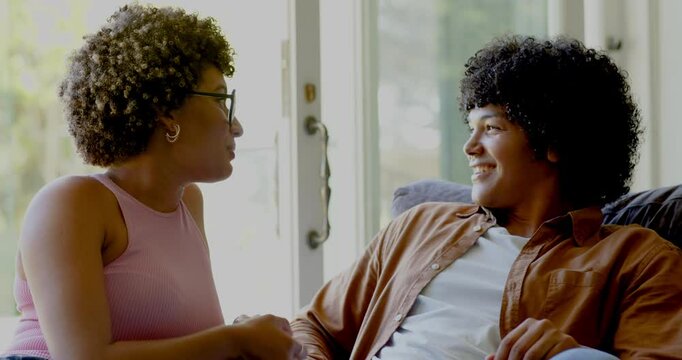 Couple starting talk as woman leaning and speaking animatedly on couch by sliding door for support