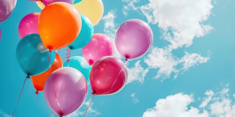 A colorful collection of balloons against a clear blue sky with fluffy white clouds