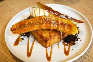 French toast with banana and honey being drizzled over it.