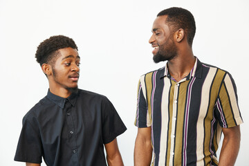 Two smiling African American men engage in a friendly conversation, showcasing joy and camaraderie...