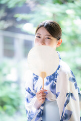 縁側に座る団扇を持った浴衣の女性のカメラ目線　奥ゆかしい女性