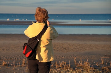 Mature woman standing on the beach and taking photo