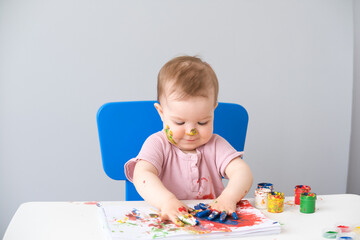 child is drawing on white sheets with finger paints