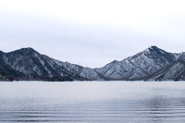 Chuzenji Lake with ripple on water surface and snow mountain background