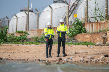 Environmental engineer or workers examining waste water along a large industrial waste water or...