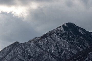 Landscape view of close-up snow covered mountain range in winter with overcast sky background