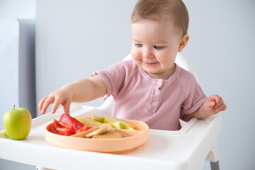 cute baby eating solid food sitting in a baby chair. weaning