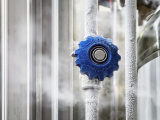 A close-up of a blue valve with nitrogen frost, indicating low temperatures in industrial conditions
