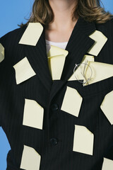 A lot of work and multitasking concept. Business woman is tired. She has got a lot of yellow stickers notes on her suit and face.