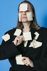 A lot of work and multitasking concept. Business woman is tired. She has got a lot of yellow stickers notes on her suit and face.