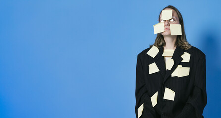 A lot of work and multitasking concept. Business woman is tired. She has got a lot of yellow stickers notes on her suit and face.