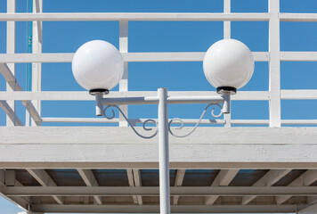 Two white light bulbs hanging from a white metal pole