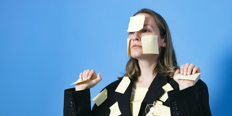 A lot of work and multitasking concept. Business woman is tired. She has got a lot of yellow stickers notes on her suit and face.
