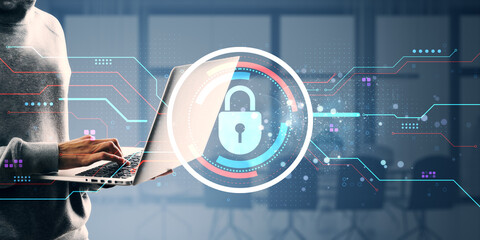 Cybersecurity concept showing person using laptop with digital lock icon overlay on blurred office background, illustrating data protection.