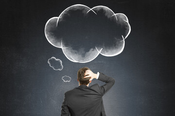 Fototapeta premium Businessman scratching head while facing chalk-drawn thought bubble on dark wall background, symbolizing brainstorming or problem-solving.