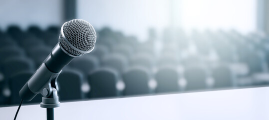 Closeup of microphone on stage in empty conference room with soft blur and ambient light in...