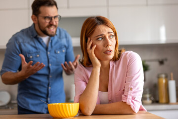 domestic dispute unfolds as a woman passionately gestures while speaking, blocking her out with his...
