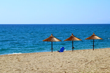 Bamboo sunshades at the sea under blue sky, summer beach holiday background (Gythio bay, Greece)