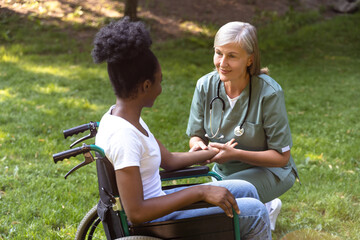 Nurse and a female on a wheelchair in the park