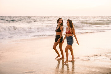 Friends walking on the beach at sunset enjoying their holiday