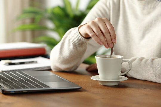 Student hand stirring coffee at home